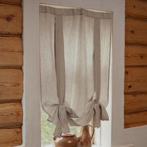 May include: A window with a white frame and a light brown linen curtain tied back on each side. Two brown ceramic pots sit on the windowsill.