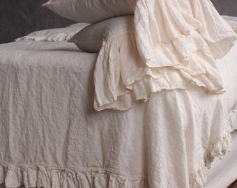 May include: A white linen bedspread with a ruffled edge. The bedspread is made of a soft, natural fabric and has a relaxed, casual look.