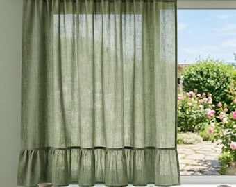 May include: A sage green curtain with a ruffled bottom hem hangs from a dark metal rod over a window. The fabric has a visible weave texture, allowing light to pass through. The curtain covers the left side of the window frame, revealing a garden.