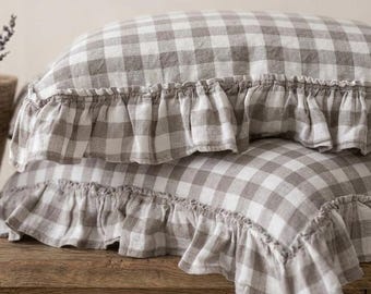 May include: Two rectangular pillows featuring a beige and white gingham check pattern. Each pillow is finished with a gathered fabric ruffle along the edges, creating a textured border. The fabric appears to have a woven, linen-like texture.