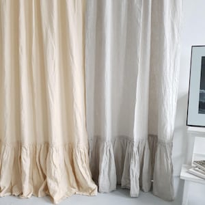 May include: Two linen curtains with a ruffled bottom. The curtain on the left is a light cream color and the curtain on the right is a light gray color.