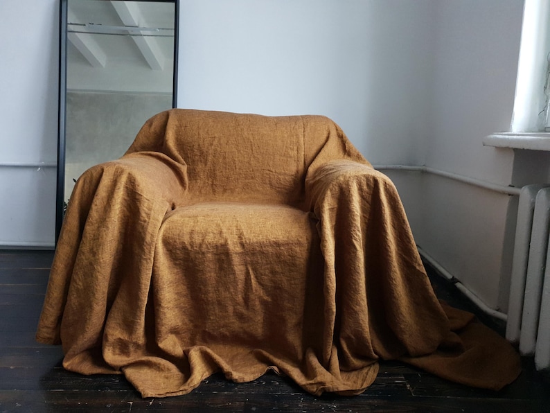 May include: A brown linen throw blanket draped over a chair. The blanket is a soft, natural color and has a textured weave.