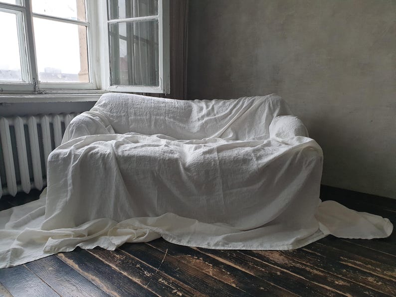May include: A white linen sofa cover draped over a couch, creating a simple and elegant look.