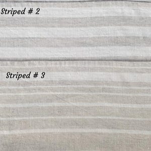 May include: Two swatches of woven fabric featuring horizontal stripes in neutral beige and off-white tones. The top section is labeled Striped # 2, while the bottom section is labeled Striped # 3, showcasing variations in stripe width and spacing.