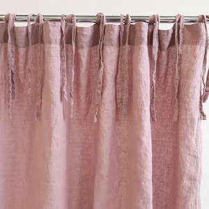 May include: Dusty rose linen curtains with a gathered top and tie-back detail. The curtains are made of a soft, natural fabric and have a relaxed, casual look.