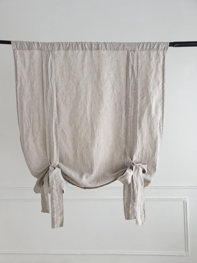 May include: A pair of beige linen curtains with a striped pattern, tied back with fabric ties.
