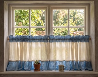 May include: A cafe curtain featuring a horizontal color-blocked design with a blue top ruffle, a central cream-colored panel, and a blue bottom ruffle. The curtain is gathered on a wooden rod and hangs in front of a window with a view of greenery.