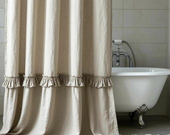 May include: Beige linen shower curtain with a ruffled trim. The curtain is in front of a white clawfoot bathtub. The bathroom has a neutral colour scheme.