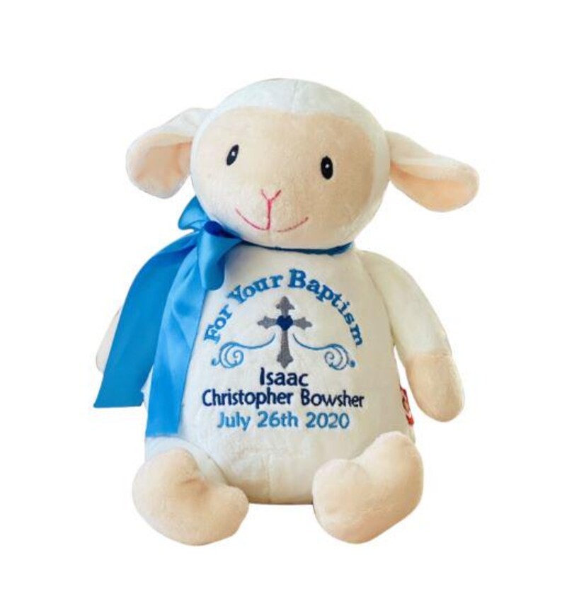 May include: A plush lamb toy with a blue ribbon around its neck. The lamb is white with beige accents and has embroidered text that reads "For Your Baptism" and the name "Isaac Christopher Bowsher" with the date "July 26th 2020".