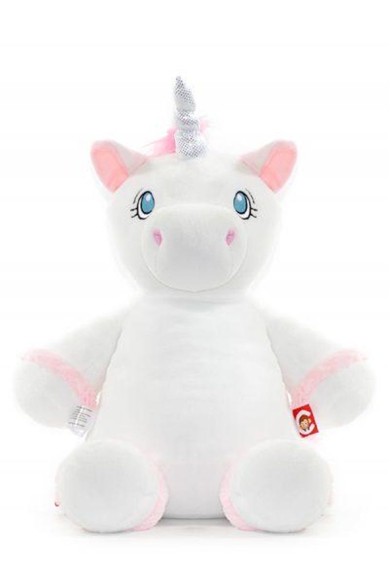 May include: A plush white unicorn stuffed animal with a silver horn, pink accents on the ears and hooves, and blue eyes. The unicorn has a soft, cuddly appearance, perfect for children. A red tag with a cartoon character is attached to the unicorn's leg.