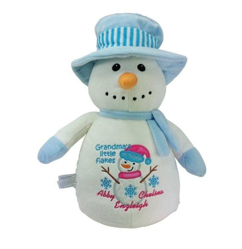 May include: A plush snowman toy with a light blue top hat and scarf. The snowman has a carrot nose, black button eyes, and a stitched mouth. The front of the snowman has an embroidered design with the text "Grandma's Little Flakes" and names.