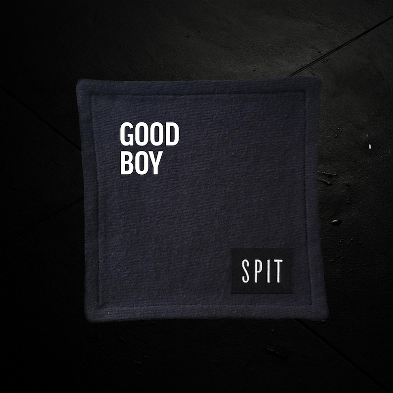K&ouml;nnte beinhalten: Ein quadratischer, dunkelblauer Untersetzer mit dem wei&szlig;en Schriftzug "GOOD BOY". Ein kleines schwarzes Rechteck unten rechts tr&auml;gt die wei&szlig;e Aufschrift "SPIT". Der Untersetzer hat einen gen&auml;hten Rand.