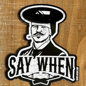 May include: Black and white sticker featuring a stylized illustration of a welder with a mustache, wearing a welding helmet and smoking a cigarette. The text "SAY WHEN" is prominently displayed below the image. The sticker has a distressed, vintage look.
