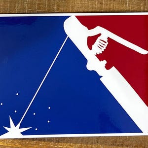 K&ouml;nnte beinhalten: Eine wei&szlig;e Silhouette eines Schwei&szlig;brenners mit Funken, die aus dem Ende fliegen, vor einem blauen und roten Hintergrund. Das Design &auml;hnelt einem Baseball-Teamlogo.