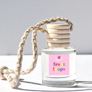 May include: A clear glass bottle with a pink label that says "Chubby Star" and "froot loops" in rainbow letters. The bottle has a wooden cap and a string for hanging.
