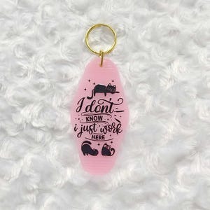 May include: Pink keychain with a black cat and the text "I don't know, I just work here".