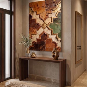Peut inclure: Une œuvre d'art murale rectangulaire présentant un motif géométrique de carreaux imbriqués dans des tons de brun, crème et vert avec des accents dorés. L'œuvre est exposée au-dessus d'une console en bois foncé avec un vase et deux récipients.