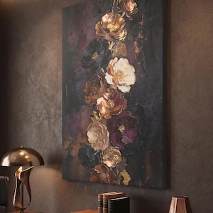 Könnte beinhalten: Vertikale Leinwandkunst mit einem Blumenarrangement aus goldenen, weißen und burgunderfarbenen Blüten vor dunklem Hintergrund. Die Blumen haben eine strukturierte, dreidimensionale Erscheinung, die einen auffälligen visuellen Effekt erzeugt. Das Kunstwerk wird in einem Raum mit warmer Atmosphäre gezeigt.