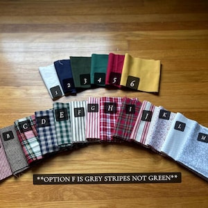 May include: A collection of fabric swatches arranged in two rows. The top row features solid colors numbered 1 through 6. The bottom row displays patterned fabrics labeled A through M, including plaids, stripes, and floral prints. Text states: **OPTION F IS GREY STRIPES NOT GREEN**.