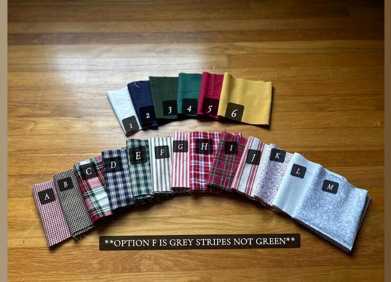 May include: A collection of fabric swatches arranged in two rows. The top row features solid colors numbered 1 through 6. The bottom row displays patterned fabrics labeled A through M, including plaids, stripes, and floral prints. Text states: **OPTION F IS GREY STRIPES NOT GREEN**.