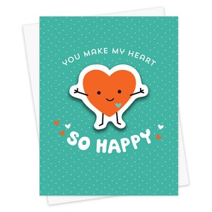 May include: A teal card with white polka dots features a cartoon heart with arms and legs. The heart is orange and has a small blue heart on its chest. The text on the card reads "You make my heart so happy".