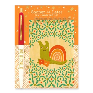 May include: A notepad and pen set featuring a snail illustration. The notepad has a woodgrain background with a green snail with a rainbow shell and a floral border. The pen is white with gold accents and the text "Getting Stuff Done". The packaging is orange with gold stars and the text "Sooner or Later Pen + Notepad Set".