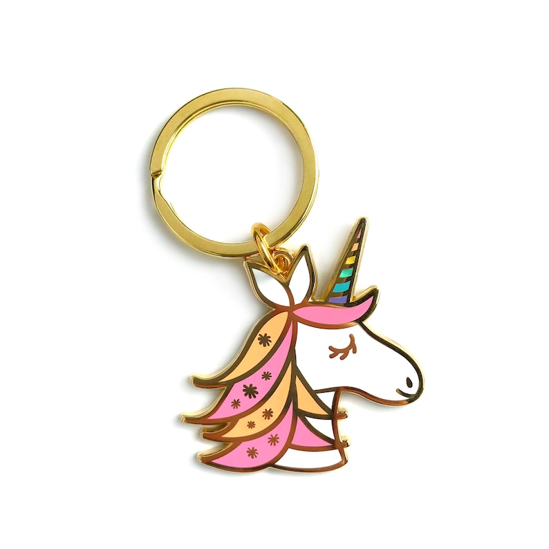May include: Gold-tone keychain featuring a unicorn head with a pink, orange, and white mane and a rainbow horn.