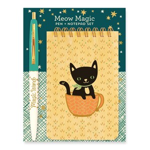 May include: A pen and notepad set with a whimsical cat theme. The pen is teal and white with "Magic Wand" text. The notepad features a black cat in a teacup design on a patterned background. The set is titled "Meow Magic".
