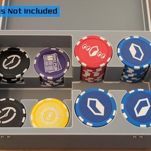 May include: A gray plastic poker chip case with various colored chips. The chips are black, purple, red, blue, and yellow, with white and silver designs. The text "Tokens Not Included" is visible.
