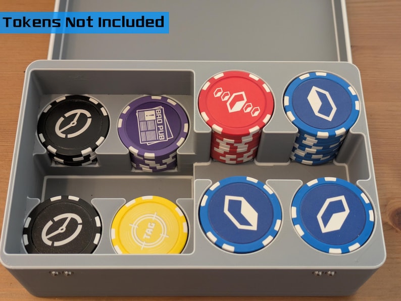 May include: A gray plastic poker chip case with various colored chips. The chips are black, purple, red, blue, and yellow, with white and silver designs. The text "Tokens Not Included" is visible.