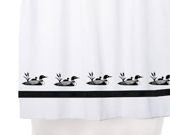 May include: White shower curtain with a black border and a repeating pattern of black loon birds with their chicks. The shower curtain is hung on a silver shower rod.
