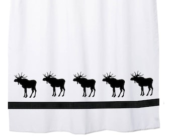 May include: White shower curtain with black moose silhouettes and black horizontal stripes. The curtain is hanging from a silver rod with metal grommets. The moose are evenly spaced along the bottom.
