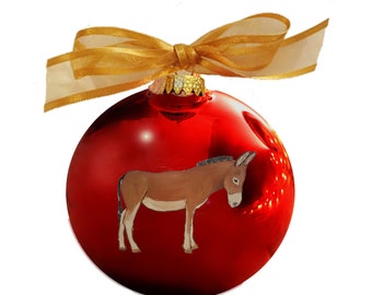 May include: A red Christmas bauble with a gold ribbon and a painted donkey on the front.