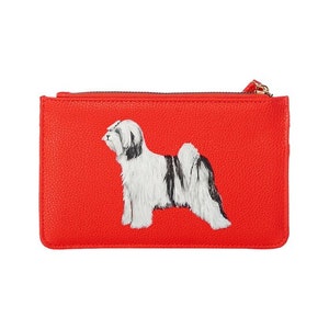 May include: A red leather clutch with a white and black Tibetan Terrier dog illustration.