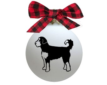 May include: White Christmas ornament with a black and white silhouette of a Bernese Mountain Dog. The ornament has a red and black plaid bow.