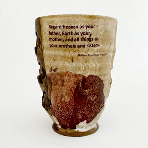 Puede incluir: Una taza de cerámica blanca con asa negra y el texto "But First, Coffee" en estilo manuscrito. La taza está sobre una superficie blanca. Ideal para bebidas calientes.