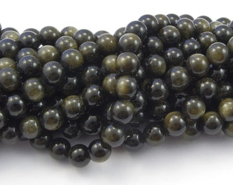 May include: A strand of round, black gemstone beads with a golden shimmer. The beads are smooth and polished, and they are arranged in a loose pile.