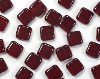 May include: A scattering of small, square, red glass beads. The beads have a slightly irregular shape and a glossy finish.