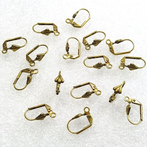 May include: A group of 14 gold-toned earring hooks with a lever back closure. The hooks are scattered on a white surface.