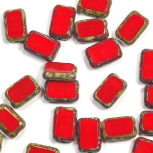 May include: A collection of red and green rectangular glass beads. The beads have a mottled green and red glaze.
