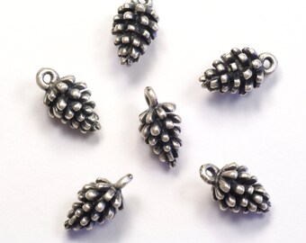 May include: Six silver-toned pine cone charms with a loop for hanging. The charms are scattered on a white background.