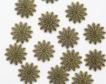 May include: A collection of 14 antique gold-toned metal decorative embellishments with a starburst design. Each embellishment has a circular center hole.