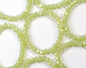 Könnte beinhalten: Nahaufnahme einer Schnur aus hellgrünen, facettierten Glasperlen. Die Perlen sind kreisförmig aufgereiht und bilden eine Halskette oder ein Armband.