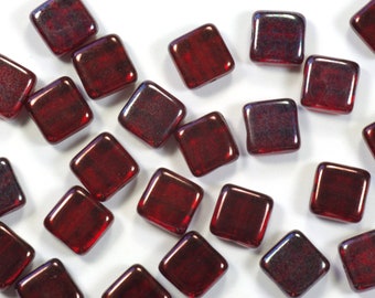 May include: A scattering of small, square, red glass beads with a subtle iridescent sheen.