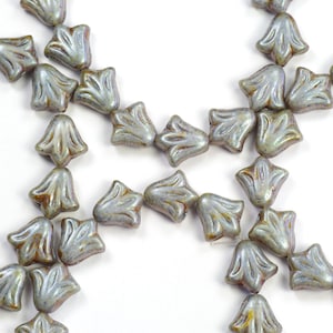 May include: A collection of gray glass flower-shaped beads with a shimmery iridescent finish.
