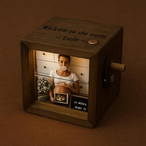May include: A wooden photo cube with the text "Welcome to the world - Emily" engraved on top. The cube displays a backlit photo of a pregnant person blowing a bubble. A small sign reads "40 weeks ready to".