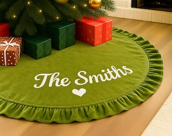 May include: A green velvet Christmas tree skirt with a ruffled edge. The skirt has the text "The Smiths" and a white heart. Presents in red, green, and brown are arranged around the tree.
