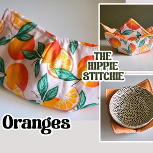 Peut inclure: Des dessous de plat faits &agrave; la main avec un motif d'oranges. Le tissu a un fond rose clair avec des oranges et des feuilles vertes. Le texte "Oranges" et "The Hippie Stichie" sont &eacute;galement visibles.