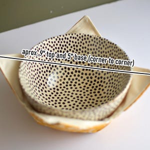 Peut inclure: Deux coussins de bol en tissu. Le bol int&eacute;rieur a un fond cr&egrave;me avec des pois noirs. Le bol ext&eacute;rieur est jaune clair. Le texte sur l'image indique : environ 23 cm de haut et 13 cm de base (coin &agrave; coin).
