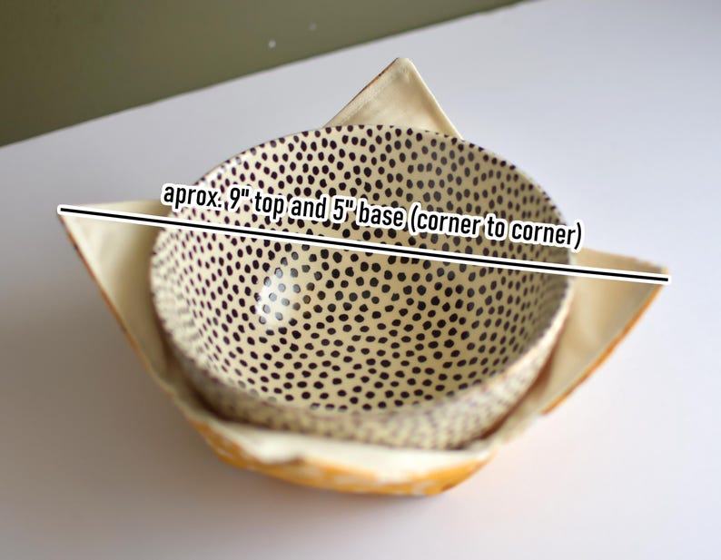 Peut inclure: Deux coussins de bol en tissu. Le bol int&eacute;rieur a un fond cr&egrave;me avec des pois noirs. Le bol ext&eacute;rieur est jaune clair. Le texte sur l'image indique : environ 23 cm de haut et 13 cm de base (coin &agrave; coin).